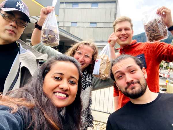 Group picture in front of a factory building. All the people are holding biscuits in the camera