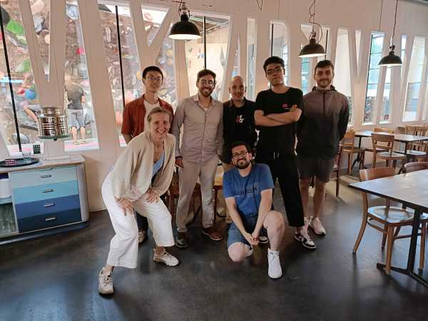 Group picture in a cafeteria in the background of a climbing wall