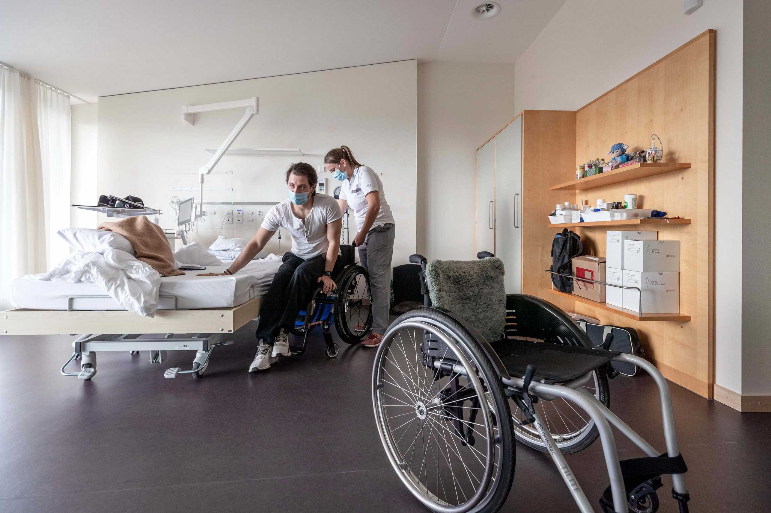 Enlarged view: An SCI person being assisted by a nurse to transfer from a hospital bed to a wheelchair